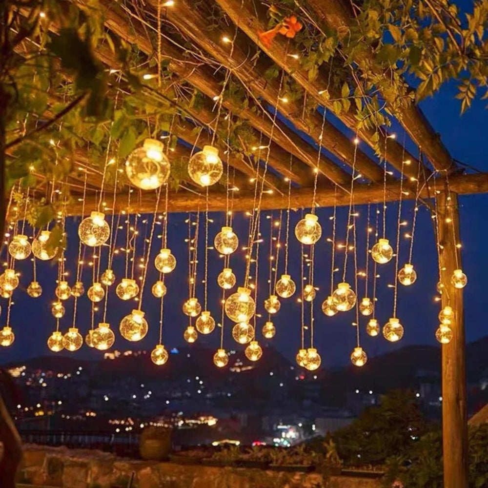 Cortina luminosa con bolas colgantes — ambiente cálido y festivo 