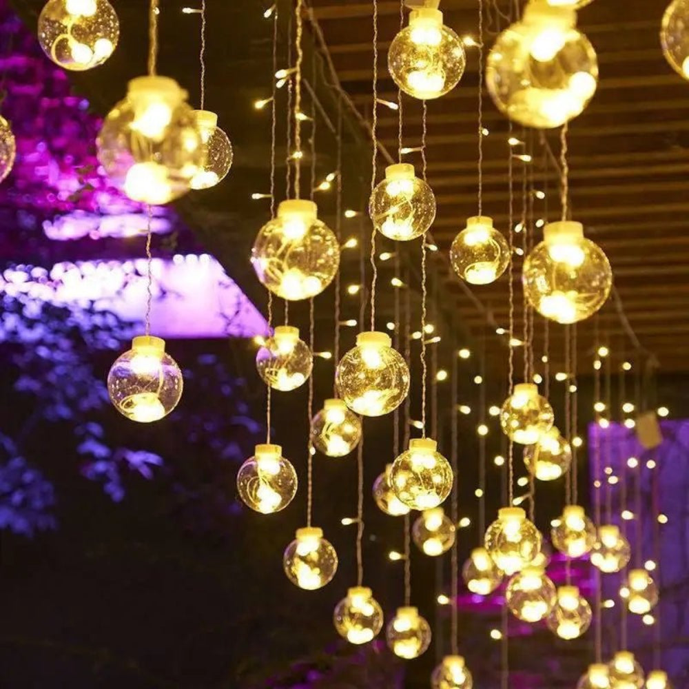 Cortina luminosa con bolas colgantes — ambiente cálido y festivo 