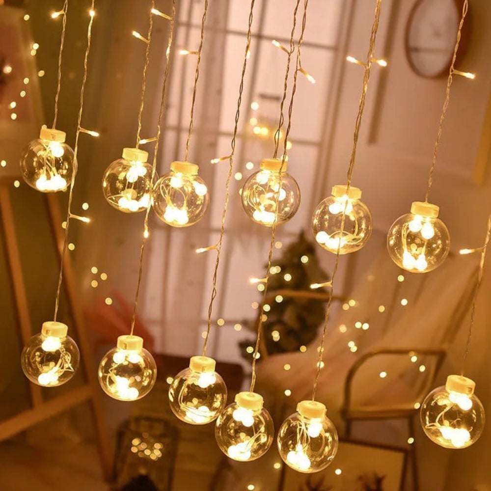Cortina luminosa con bolas colgantes — ambiente cálido y festivo 