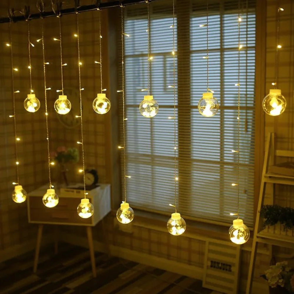 Cortina luminosa con bolas colgantes — ambiente cálido y festivo 